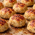 Albóndigas de pollo sin pan y sin huevo doradas recién salidas del horno sobre papel vegetal.